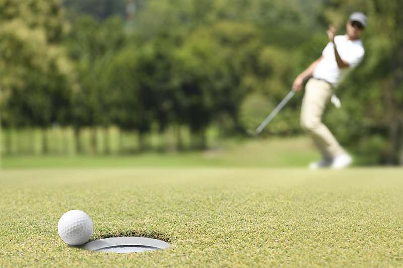 Golf ball about to drop in cup.